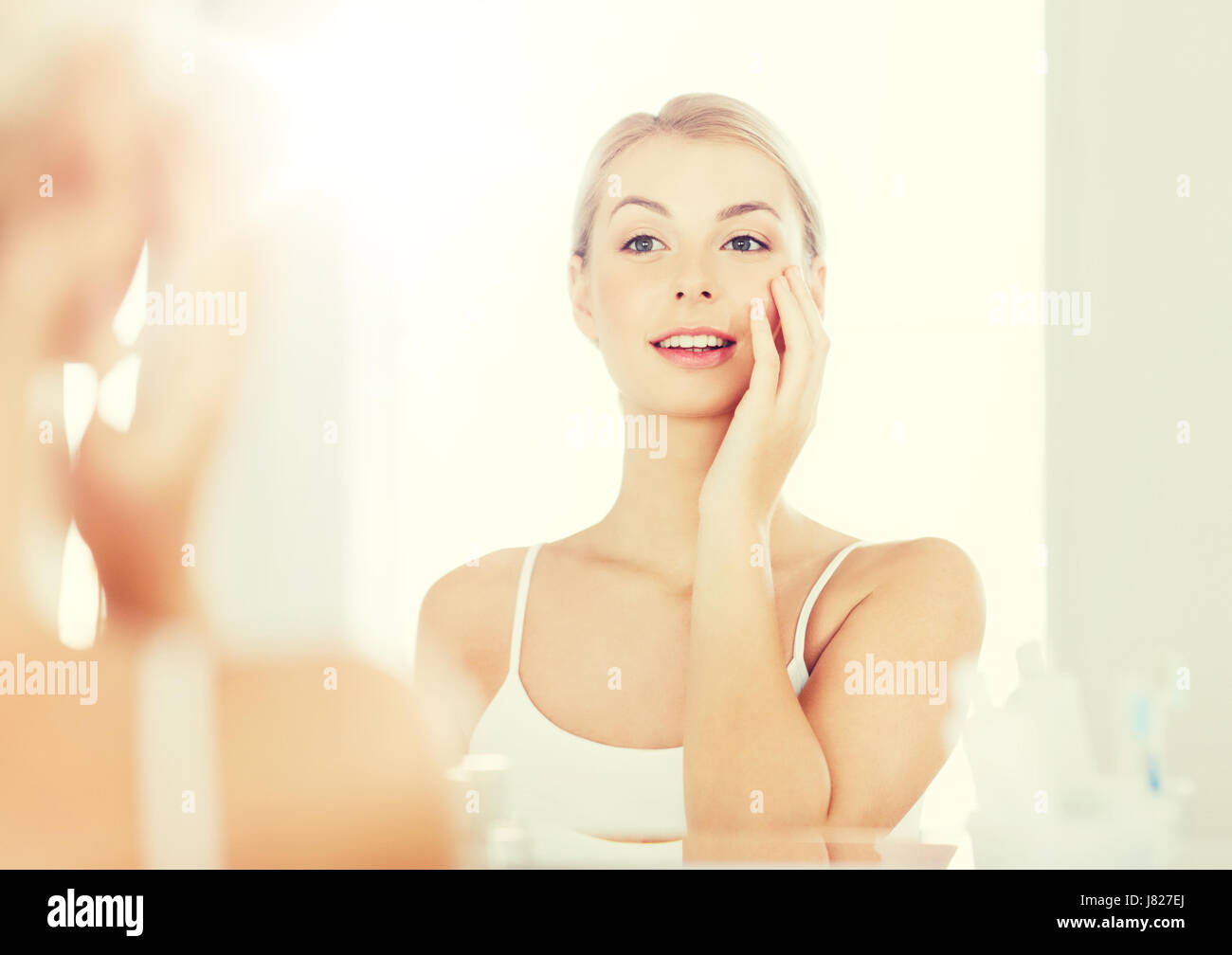 happy young woman looking to mirror at bathroom Stock Photo - Alamy