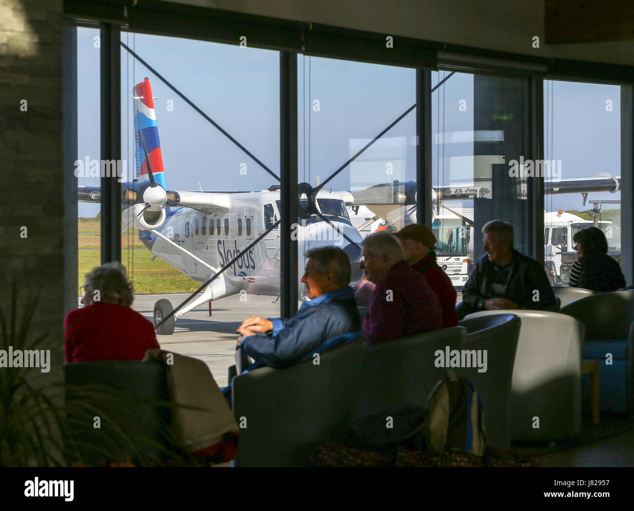 Passenger waiting area with people waiting to board a flight and a plane in the background at Land's End Airport, St. Just, Cornwall, England UK Stock Photo