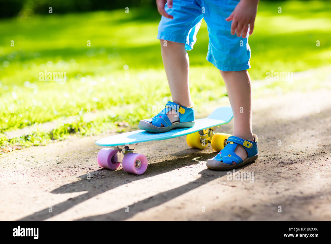 Child riding skateboard in summer park. Little boy learning to ride ...