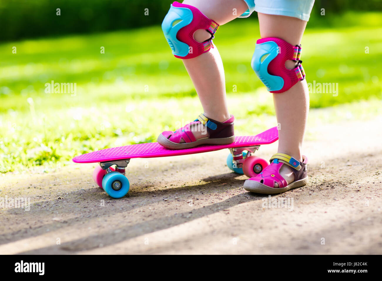 Child riding skateboard in summer park. Little girl learning to ride ...