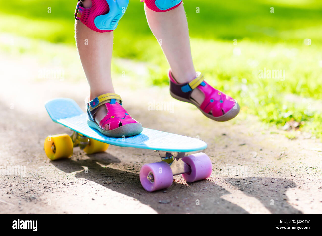 Child riding skateboard in summer park. Little girl learning to ride ...