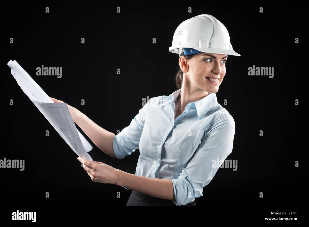 Smiling female architect in helmet holding blueprint Stock Photo - Alamy
