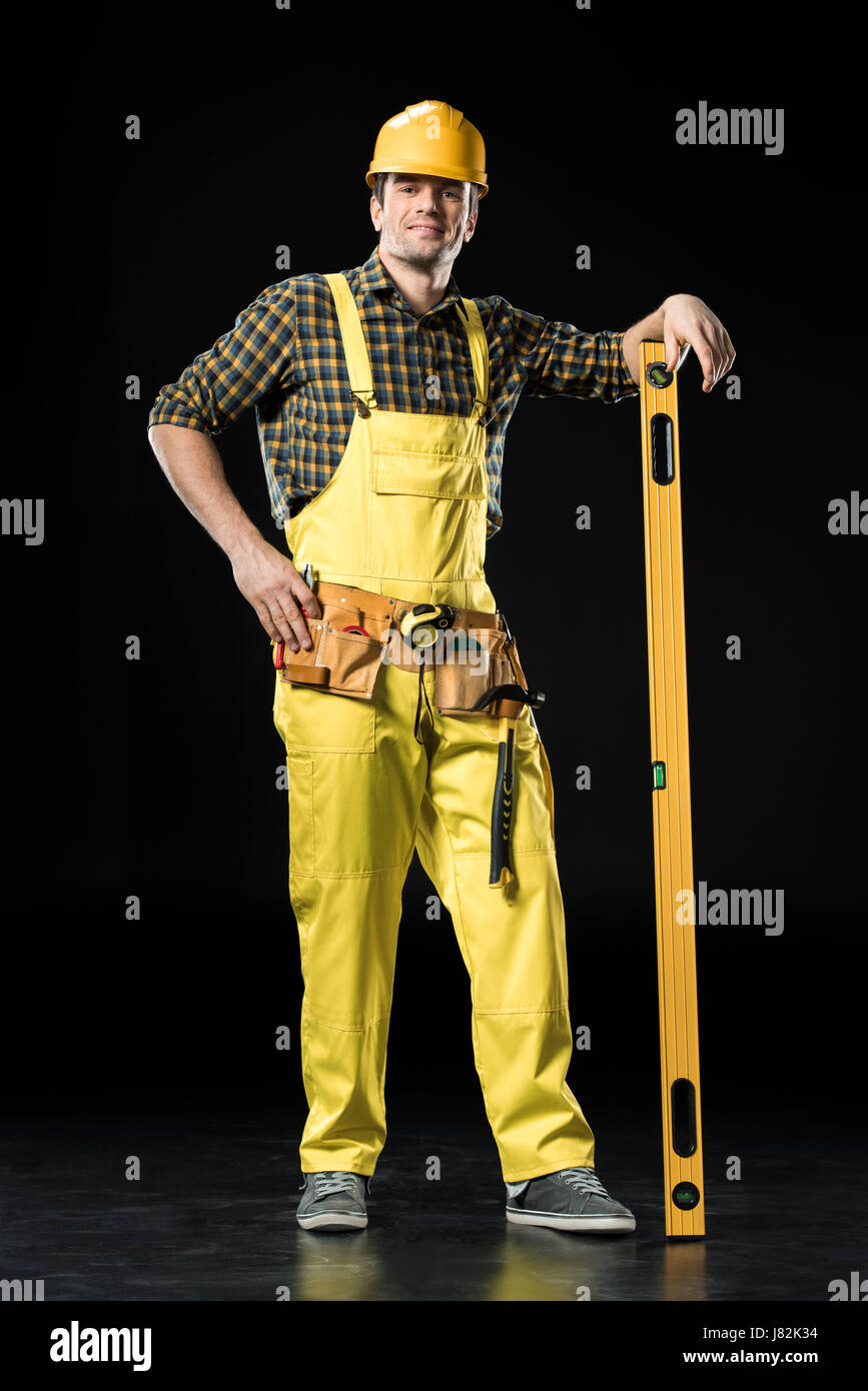 Full length portrait of male construction worker with level tool ...