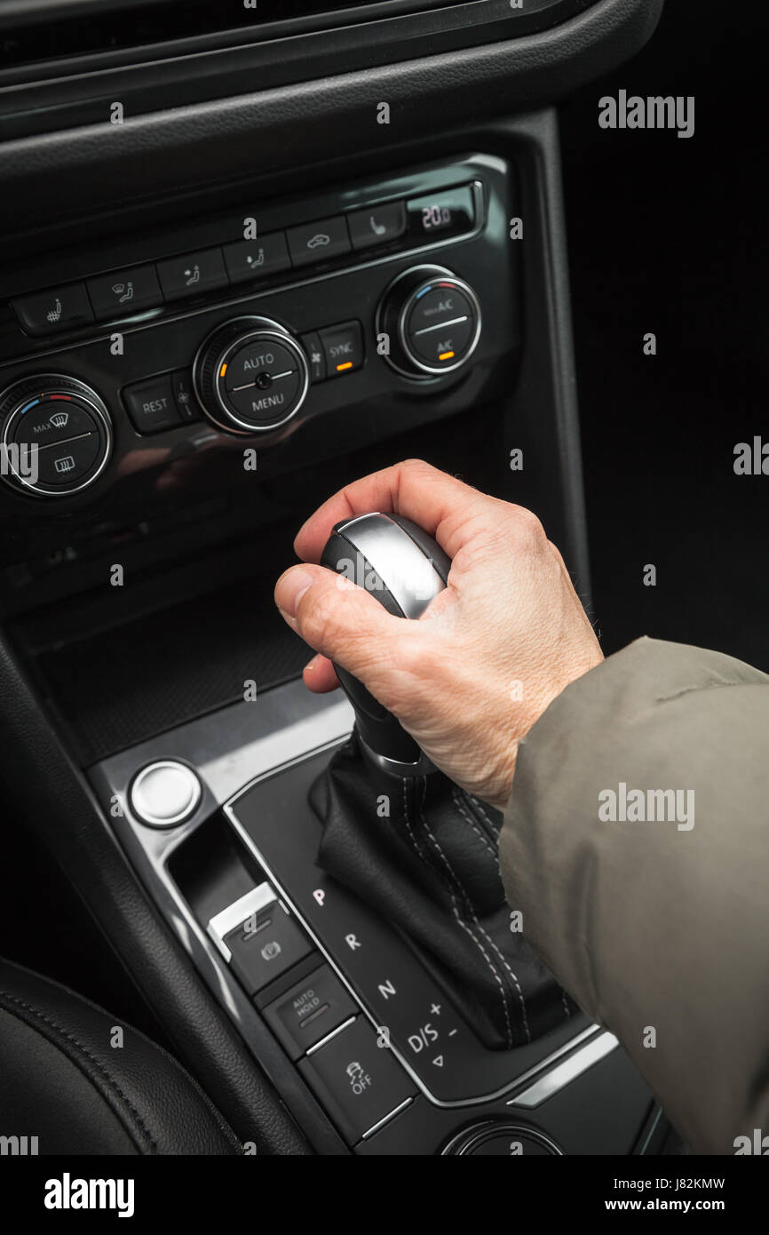 Drivers hand holds gear lever of modern luxury crossover car. Close-up photo with selective focus Stock Photo