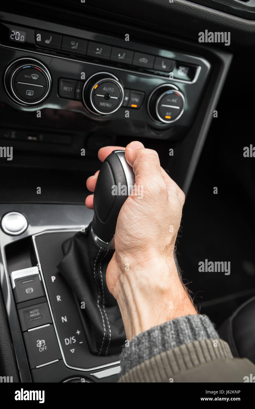 Drivers hand holds gear lever of modern luxury crossover car. Close up photo with selective focus Stock Photo