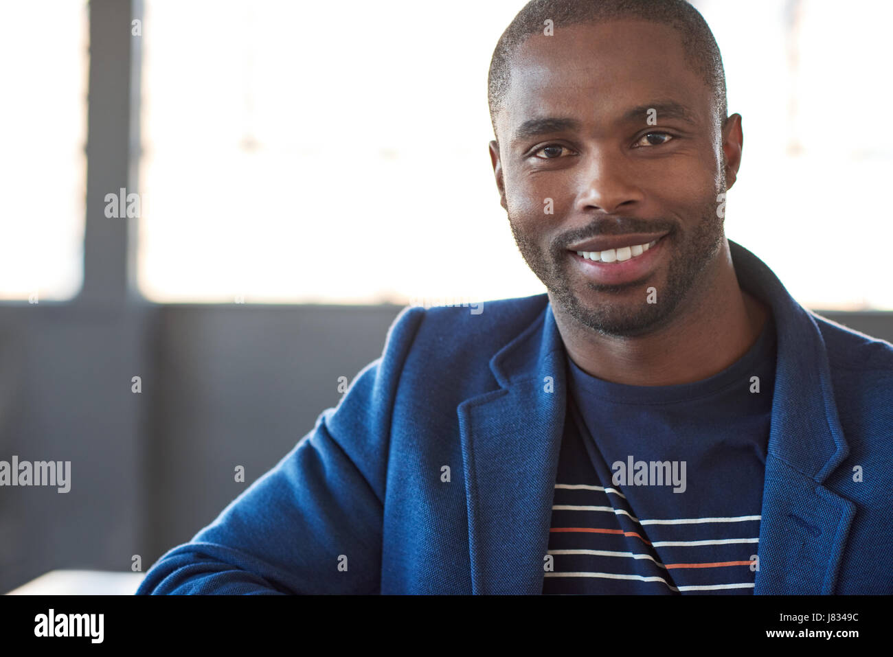 Portrait of a confident young African businessman in a blazer smiling ...