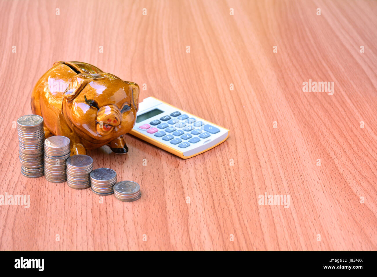 piggy bank, coins and calculator out on wood table Stock Photo - Alamy