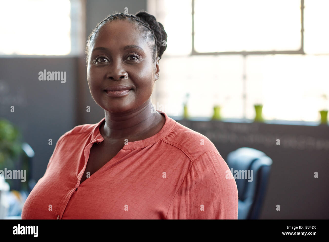 Portrait of a casually dressed young African businesswoman smiling confidently while standing alone in a modern office Stock Photo