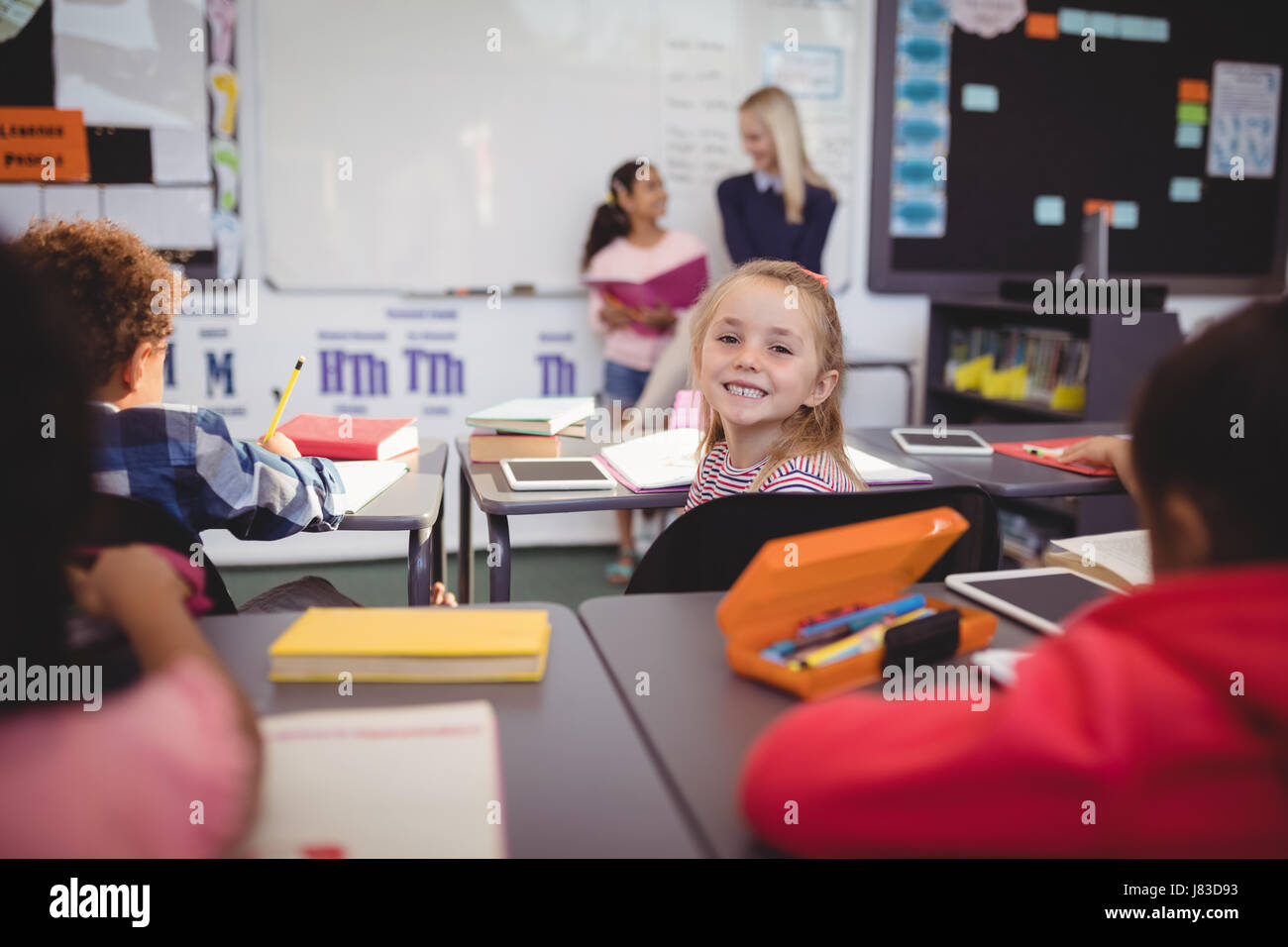 Portrait of smiling schoolgirl sitting in classroom at school Stock ...