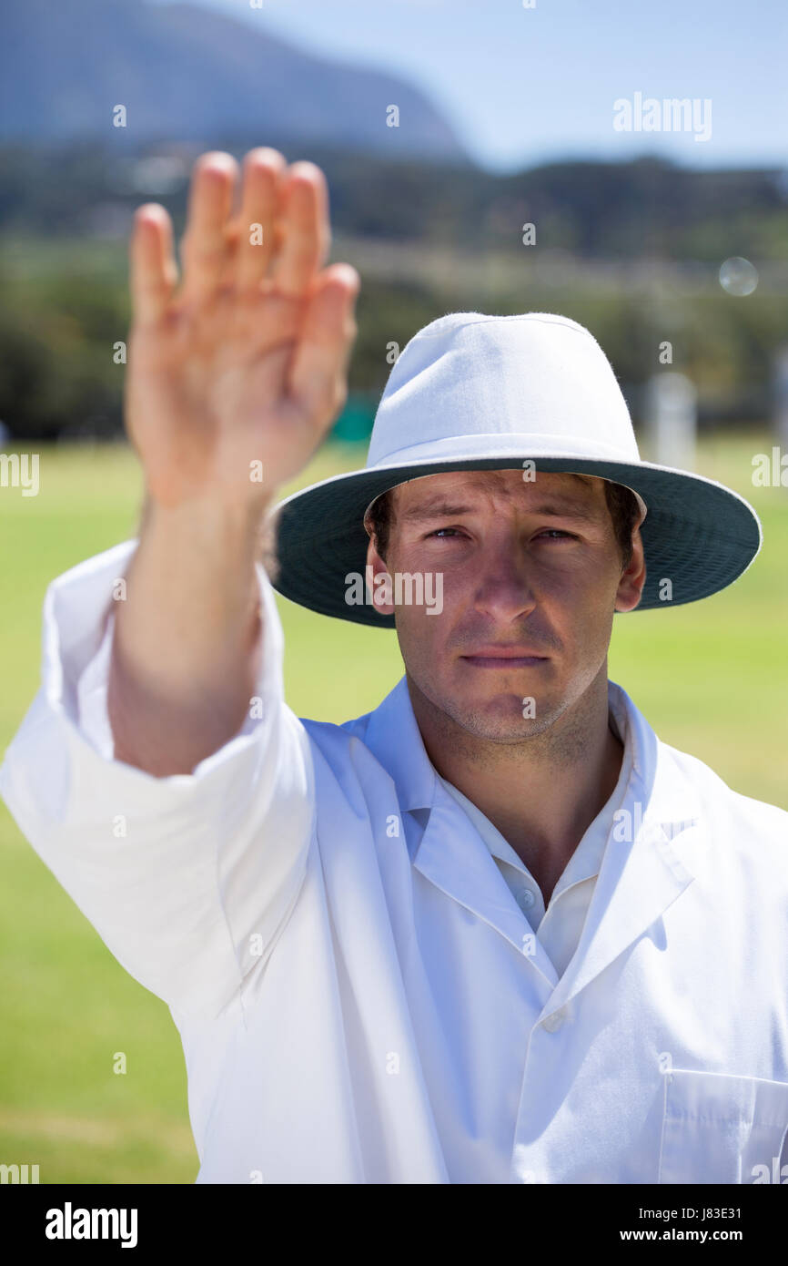 Portrait of cricket umpire signaling bye sign during match against blue sky on sunny day Stock Photo