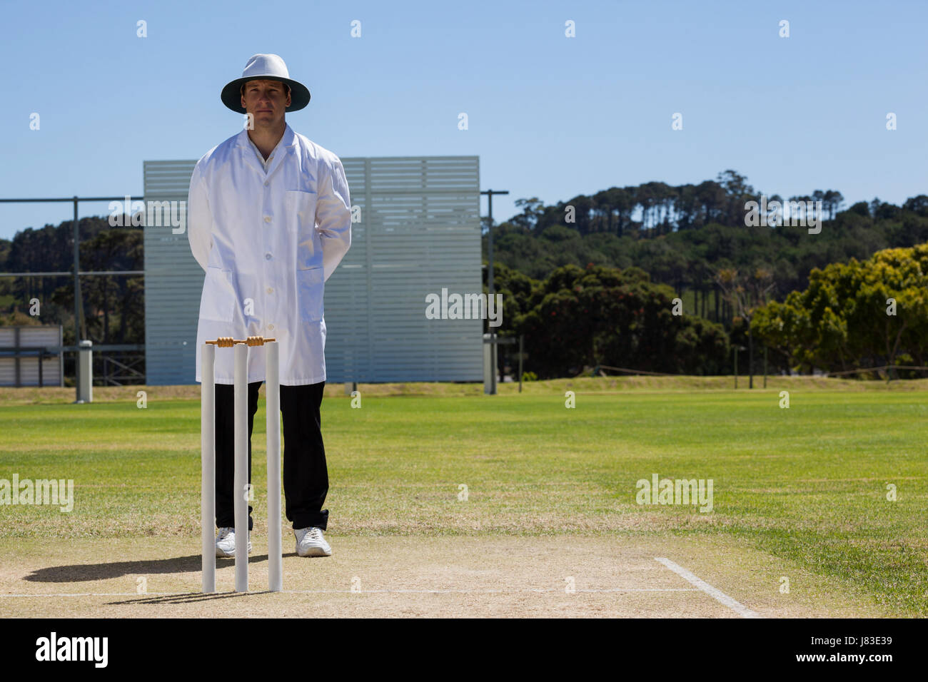 Full length of umpire standing behind stumps during cricket match on