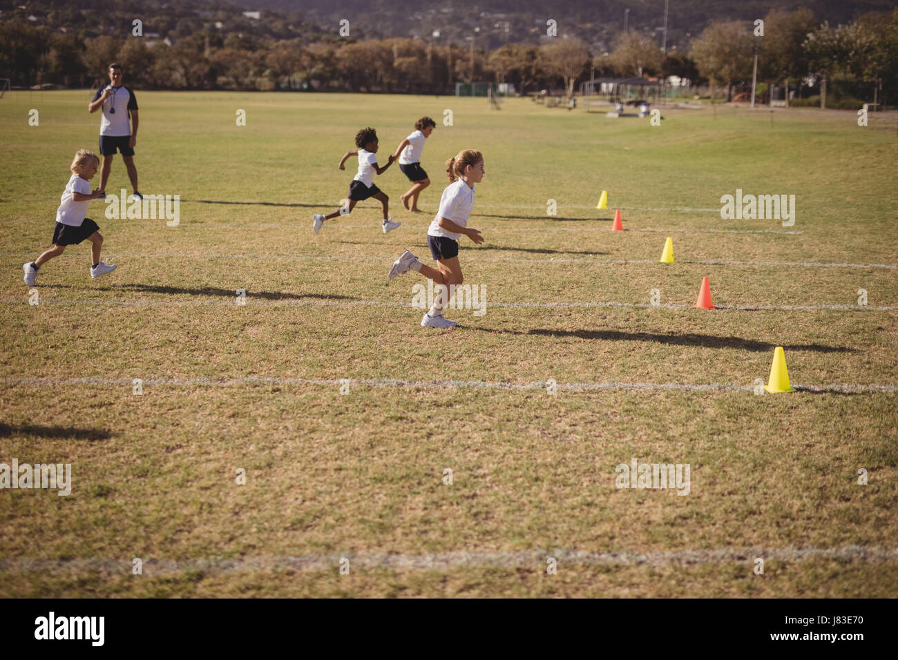 Schoolgirls running during competition in park Stock Photo