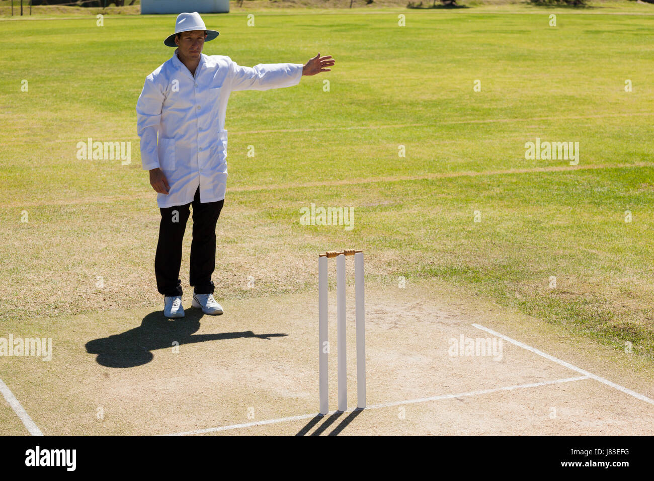 Cricket umpire signalling no ball during match on sunny day Stock Photo