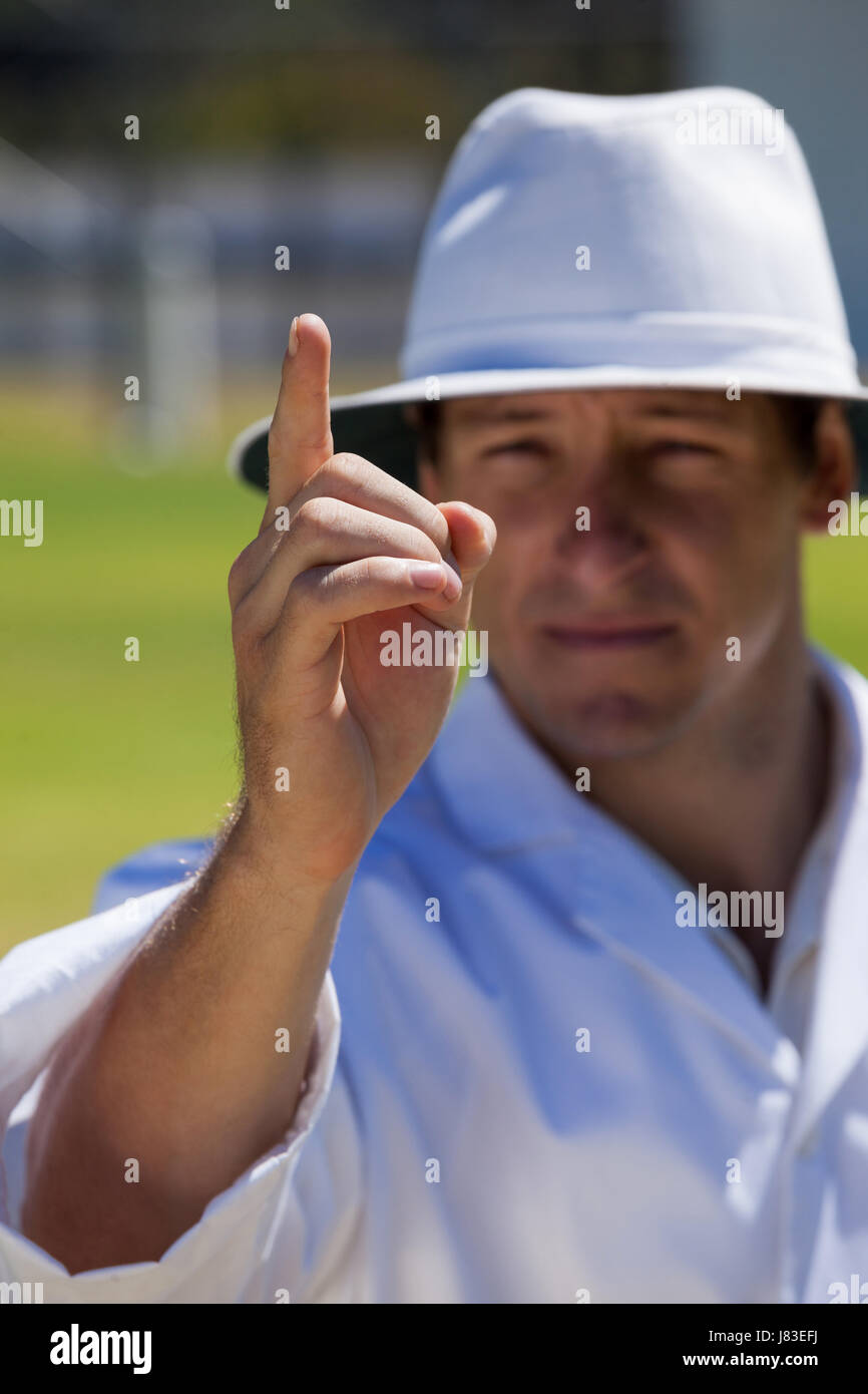 Umpire signalling out during match on sunny day Stock Photo