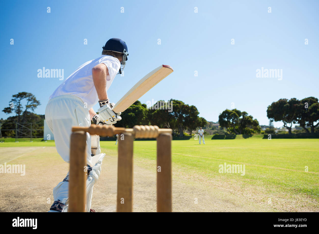 Side view of cricket player batting while playing on field against clear sky Stock Photo