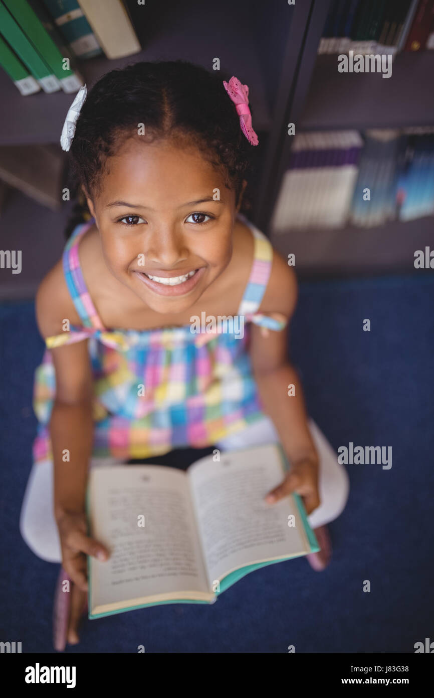 Portrait smiling schoolgirl reading book in library at school Stock ...