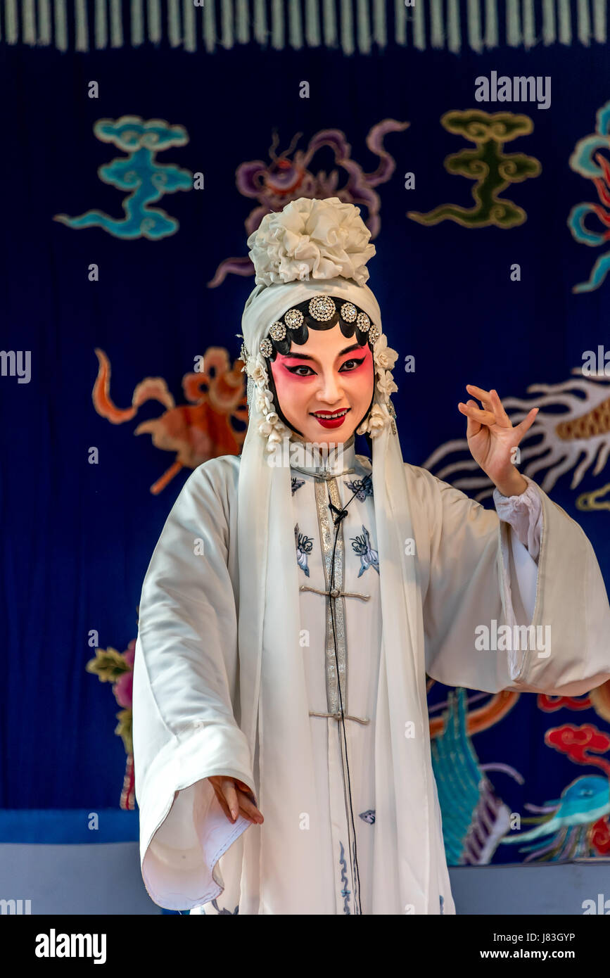 A female performer of Peking opera or Kunqu opera dressed in white before colorful tapestry performs at Cangpo Ancient Village, Yongjia County, China. Stock Photo