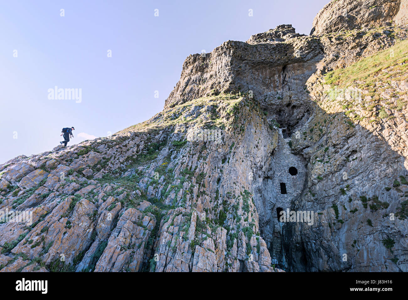 Man climbing cliff at Culver Hole, Gower, Wales, UK Stock Photo
