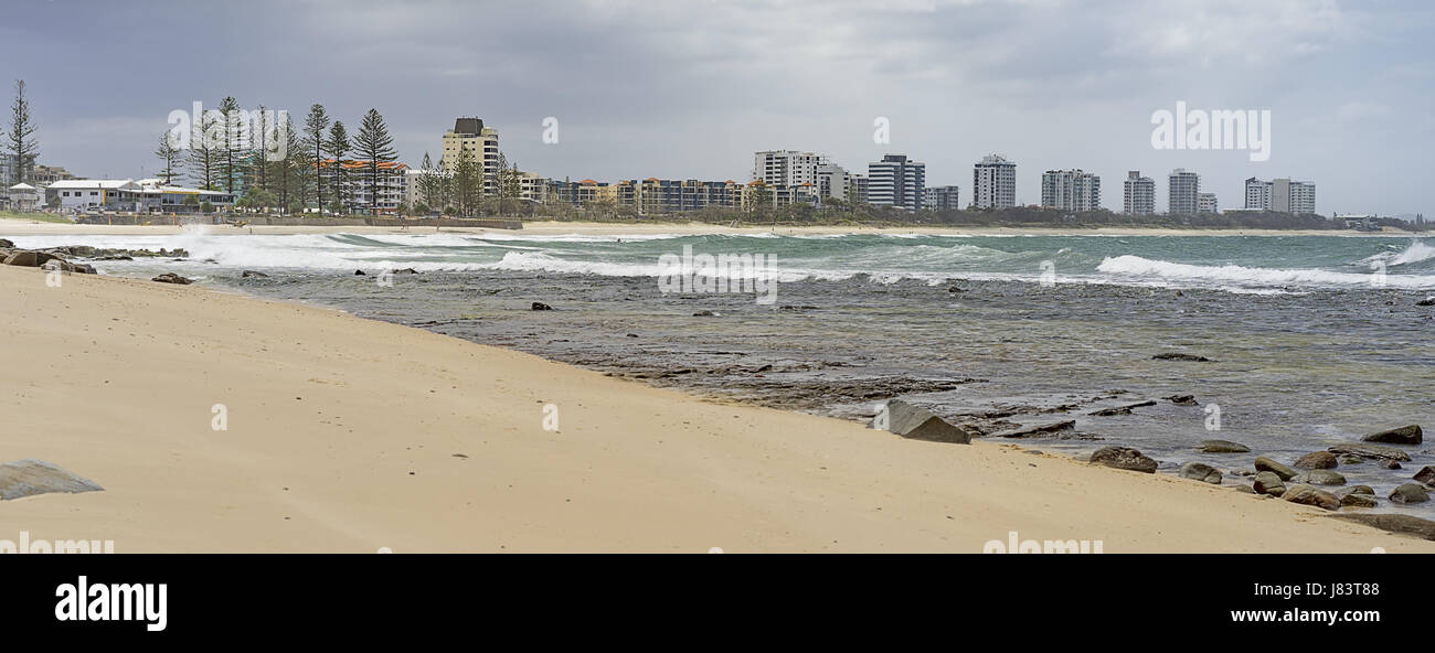 Panorama of Sunshine Coast foreshore at Alexandra Headlands Mooloolaba with surf, sand, rocky seafront and cloudy sky Stock Photo