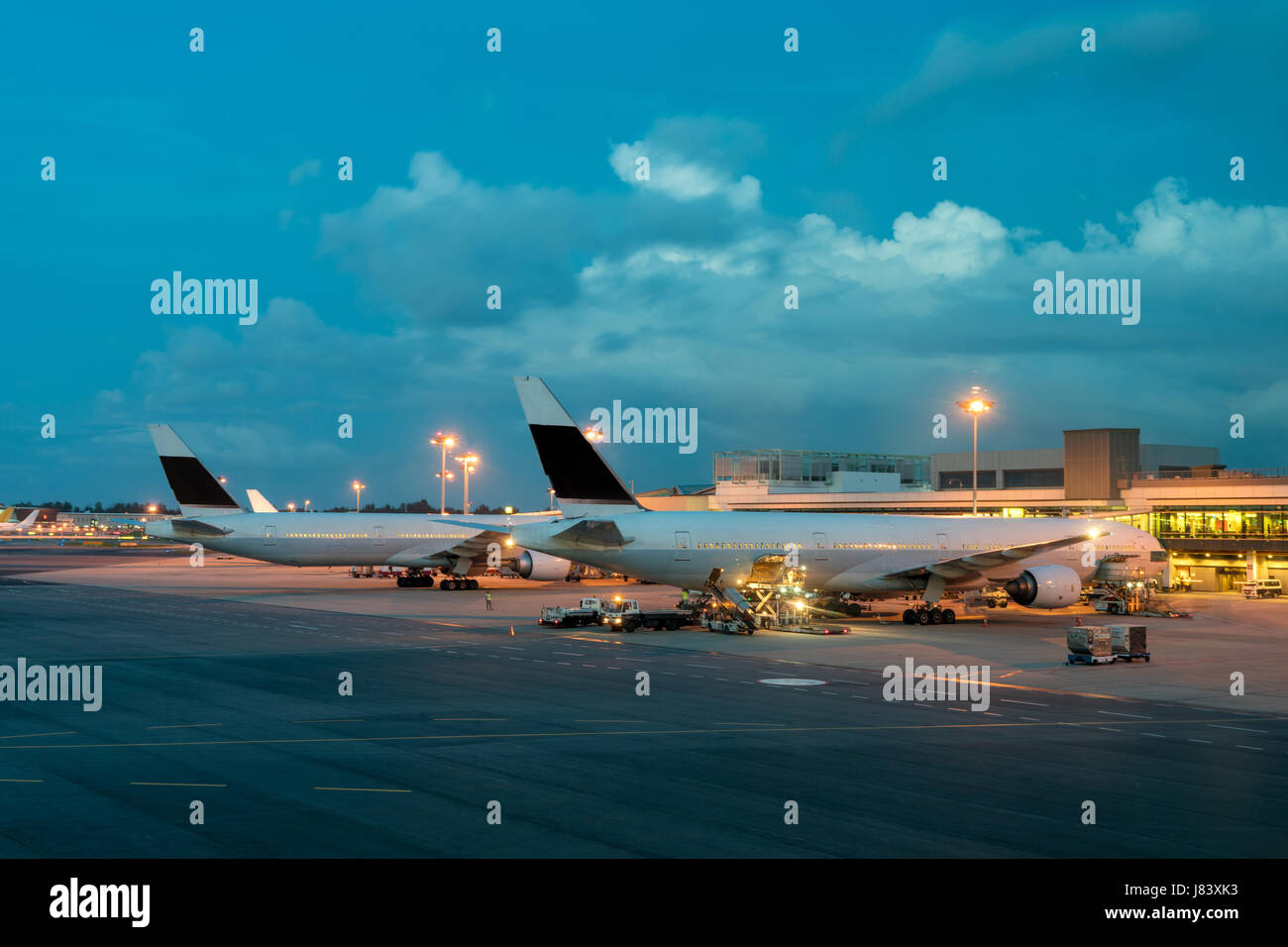 Passenger airplane on runway near the terminal in an airport at night. Airplane parking at departure gate in airport. Stock Photo