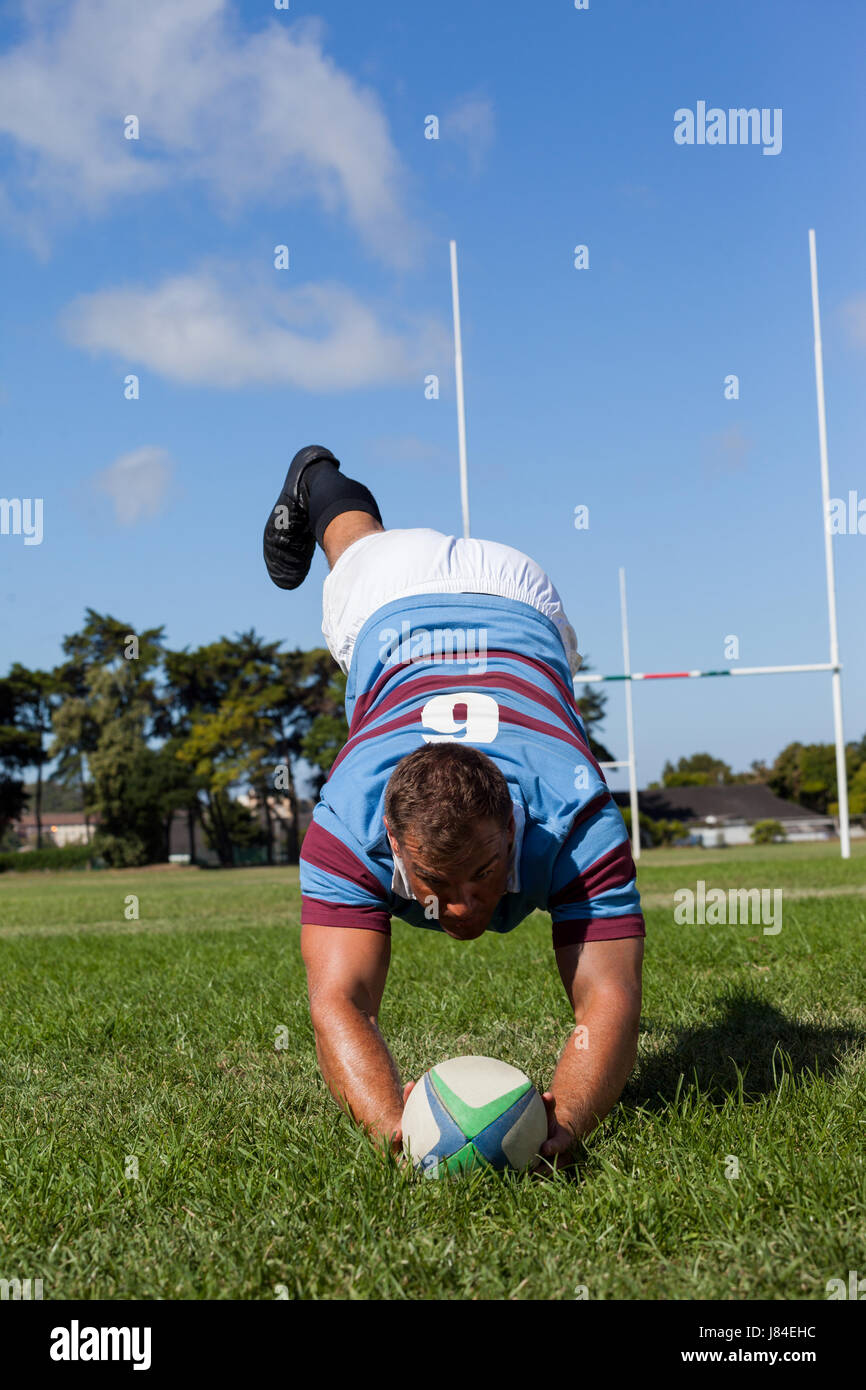 Full length of player playing rugby on field during sunny day against ...