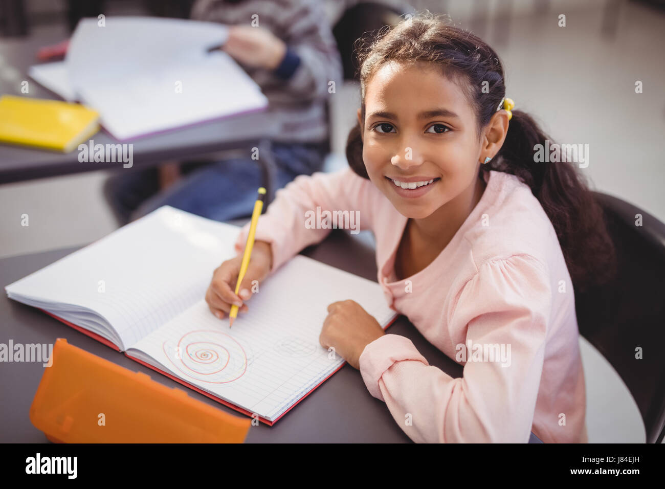 Portrait of schoolgirl drawing in book in classroom at school Stock ...