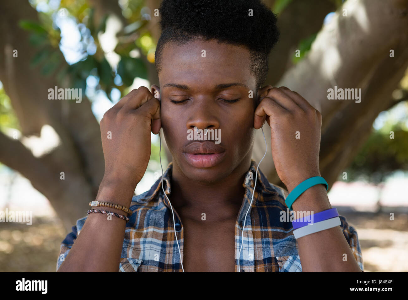 Young man with earphones listening to music in the park Stock Photo