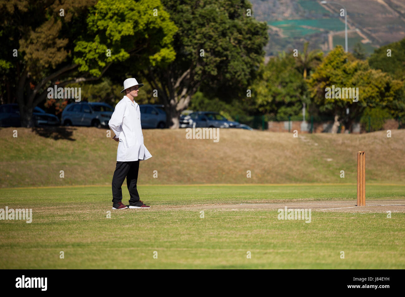 Full length of umpire standing on cricket field during sunny day Stock Photo