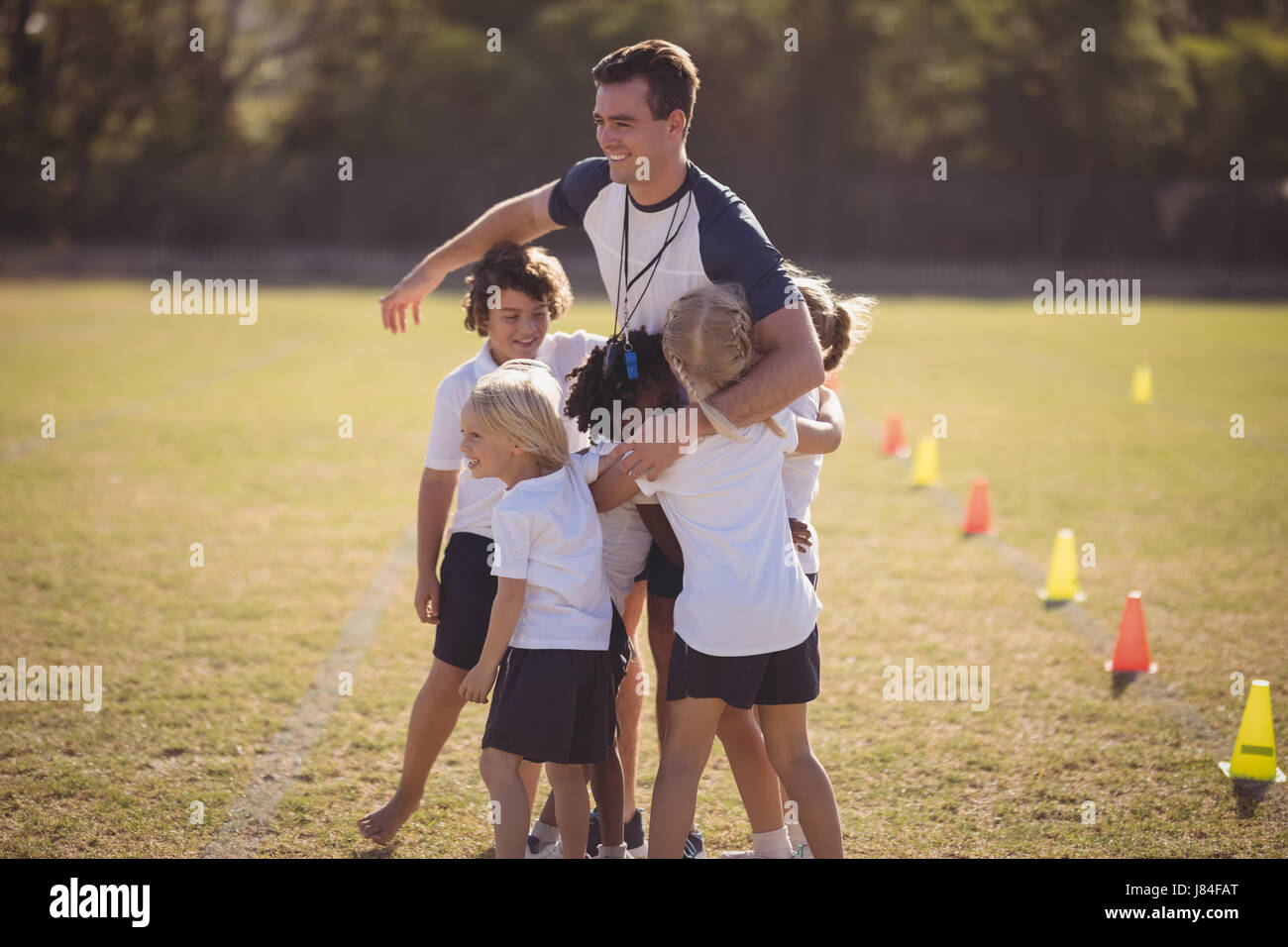 Schoolgirls embracing coach during competition in park Stock Photo