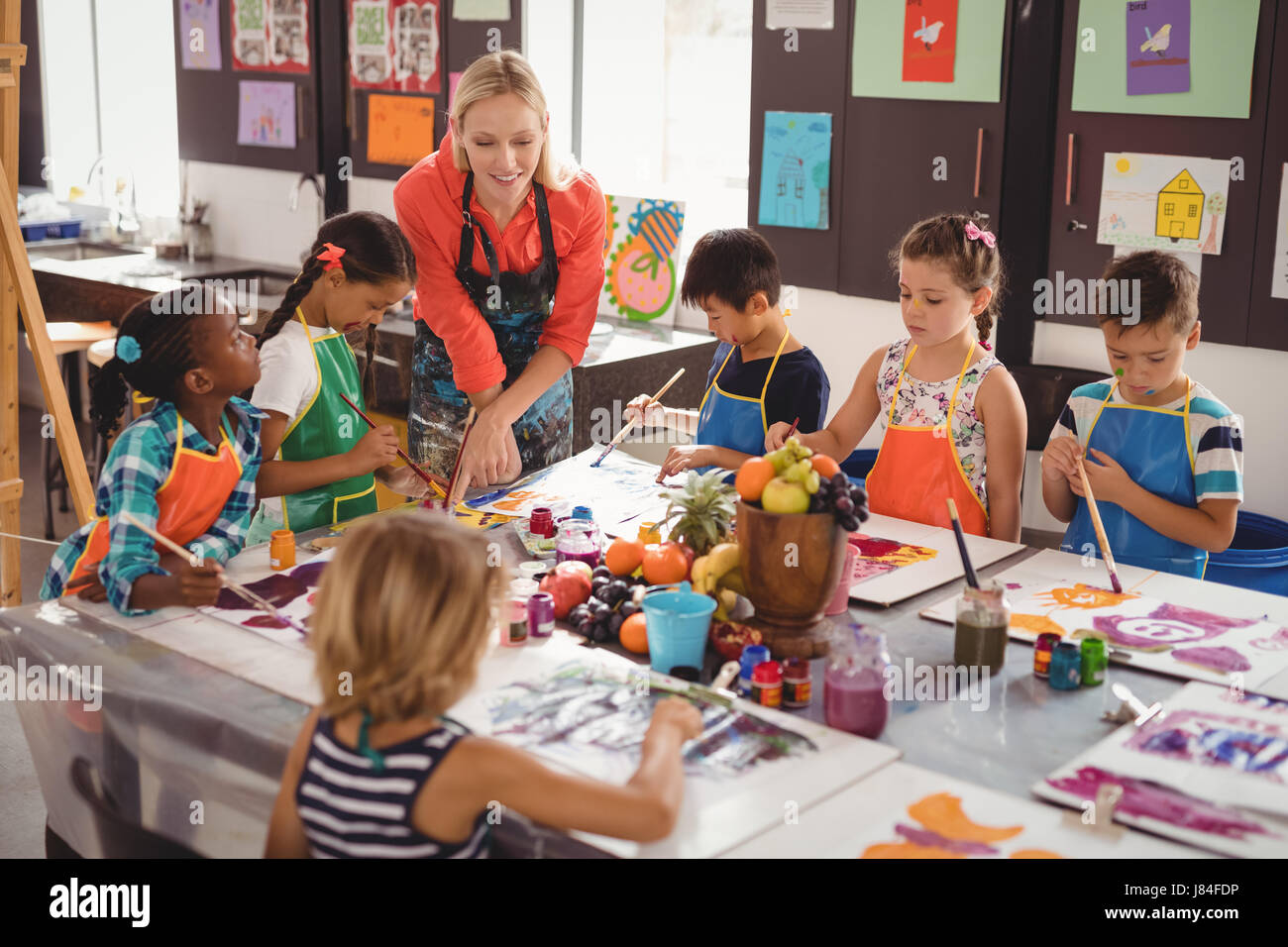 Teacher assisting schoolkids in drawing class at school Stock Photo