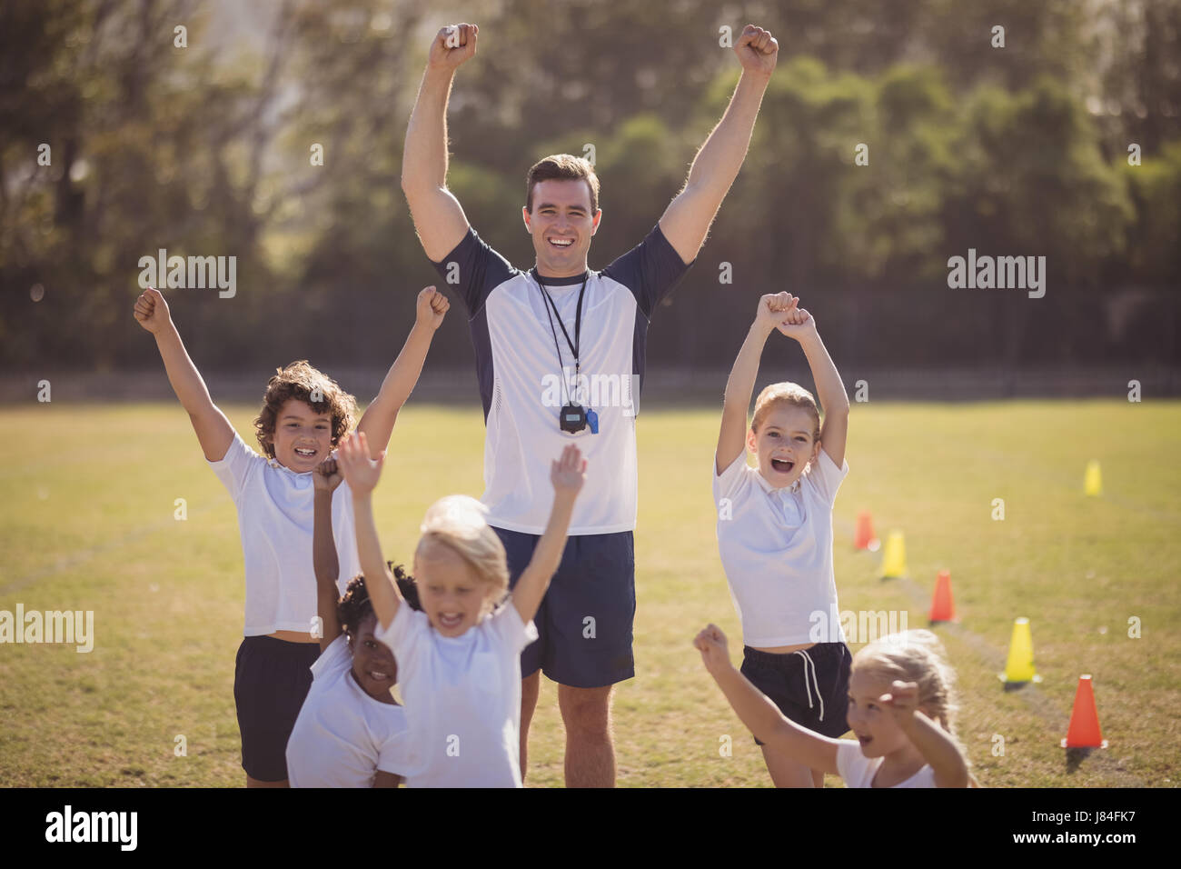 Portrait of coach and schoolgirls cheering in park during competition Stock Photo