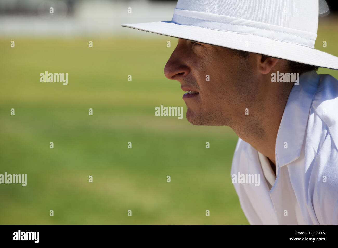 Side view of focused umpire at field during cricket match on sunny day Stock Photo