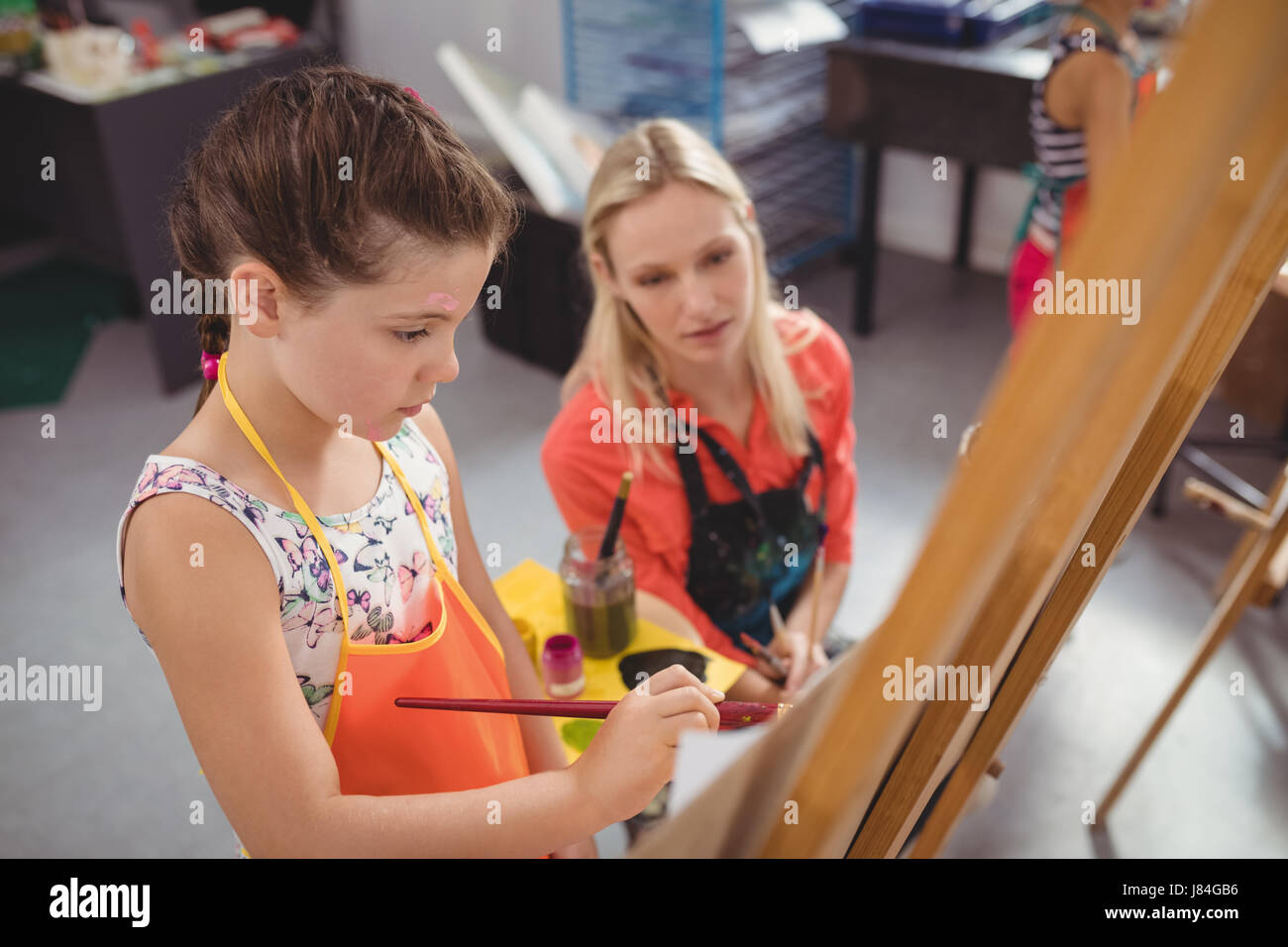Teacher assisting girl in drawing class at school Stock Photo - Alamy