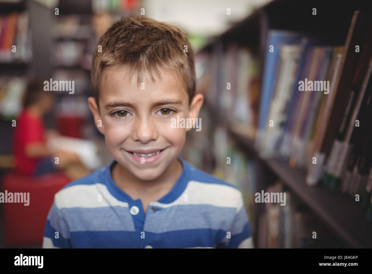 Portrait smiling schoolboy standing in library at school Stock Photo ...