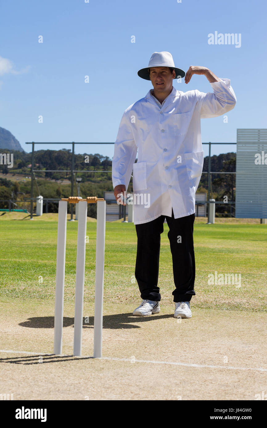 Cricket umpire signaling one short sign during match against blue sky on sunny day Stock Photo