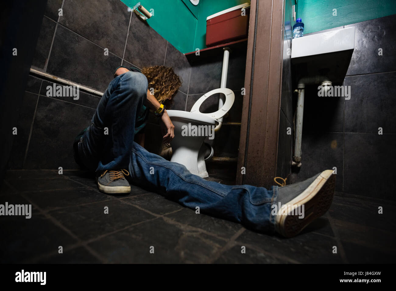 Man vomiting on toilet bowl in the washroom Stock Photo