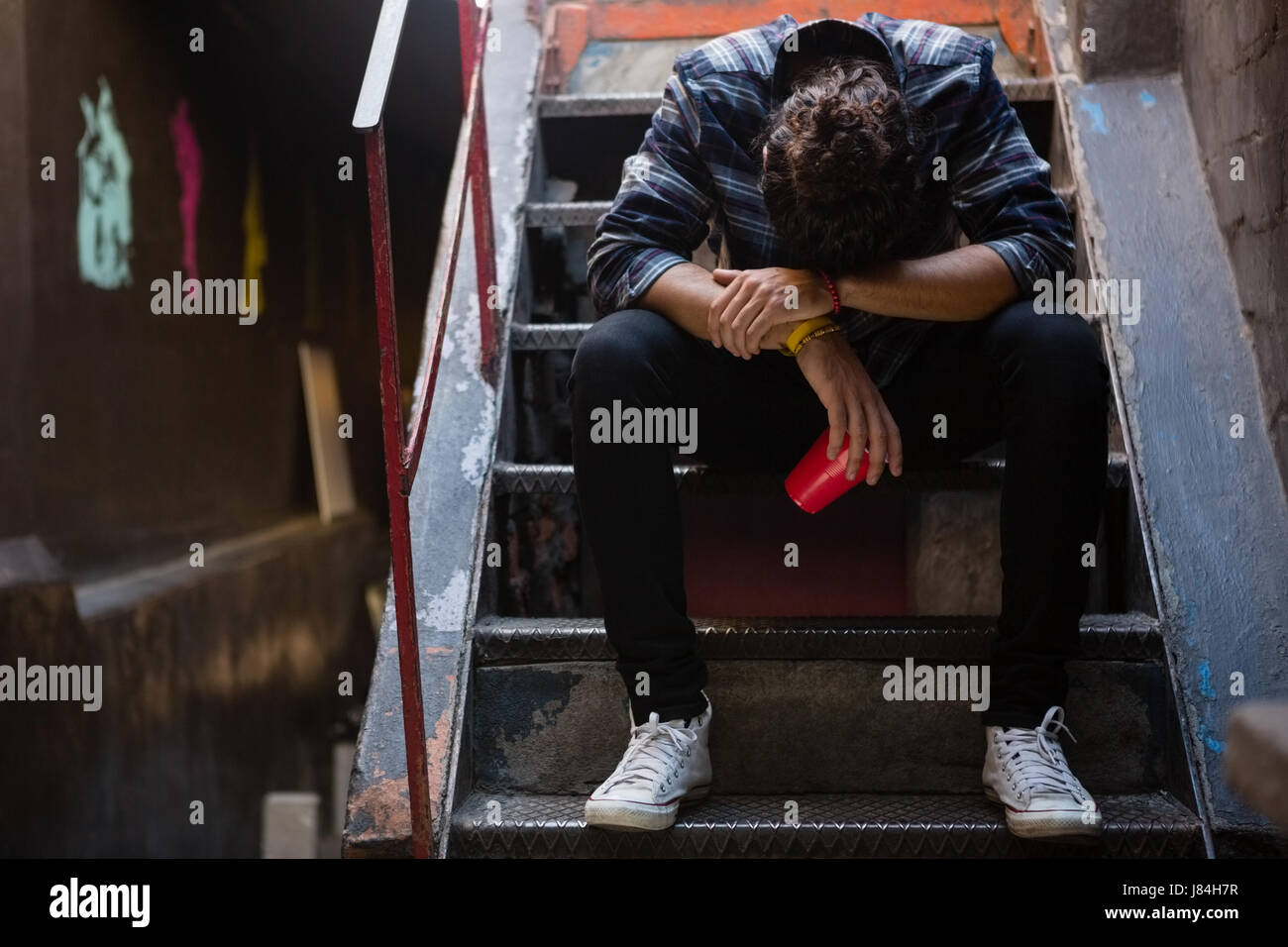 Drunk man sitting on staircase of bar Stock Photo - Alamy