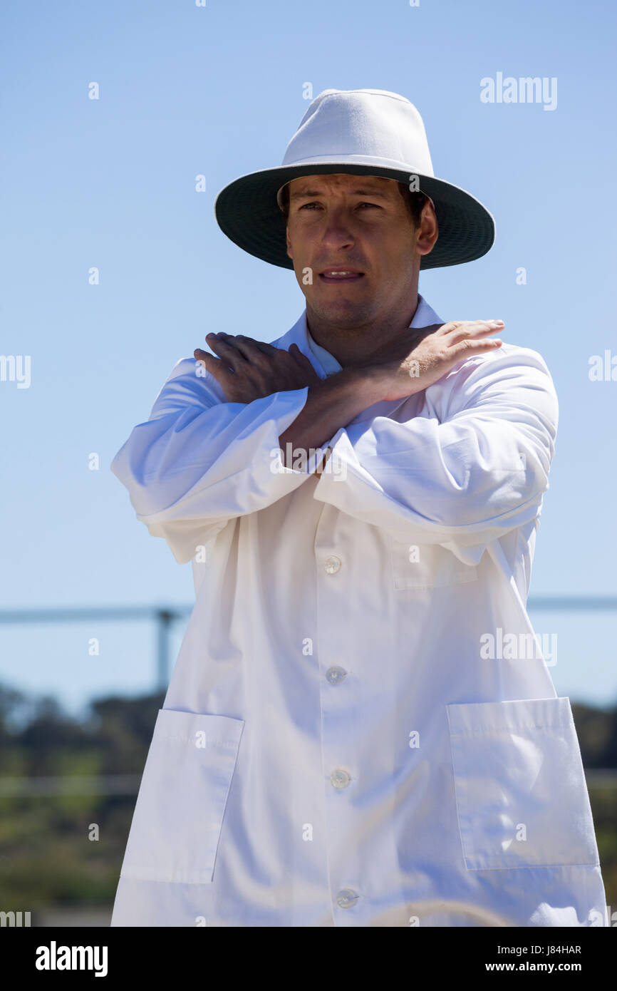 Cricket umpire signaling cancel call sign during match against blue sky on sunny day Stock Photo