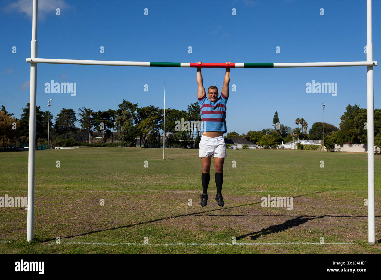 Full length of rugby player hanging on goal post at playing field