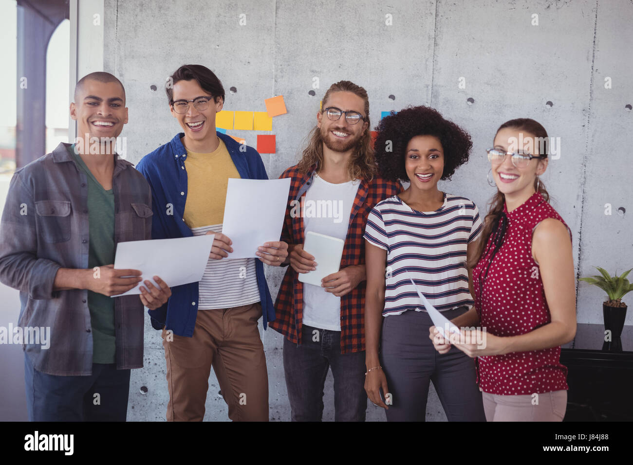 Portrait of cheerful business people standing in creative office Stock ...