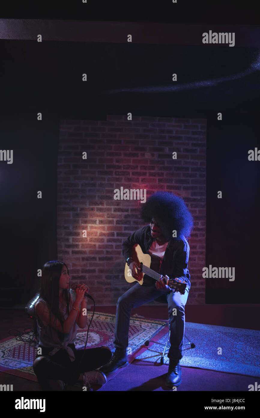 Female singer with male guitarist practicing in nightclub Stock Photo