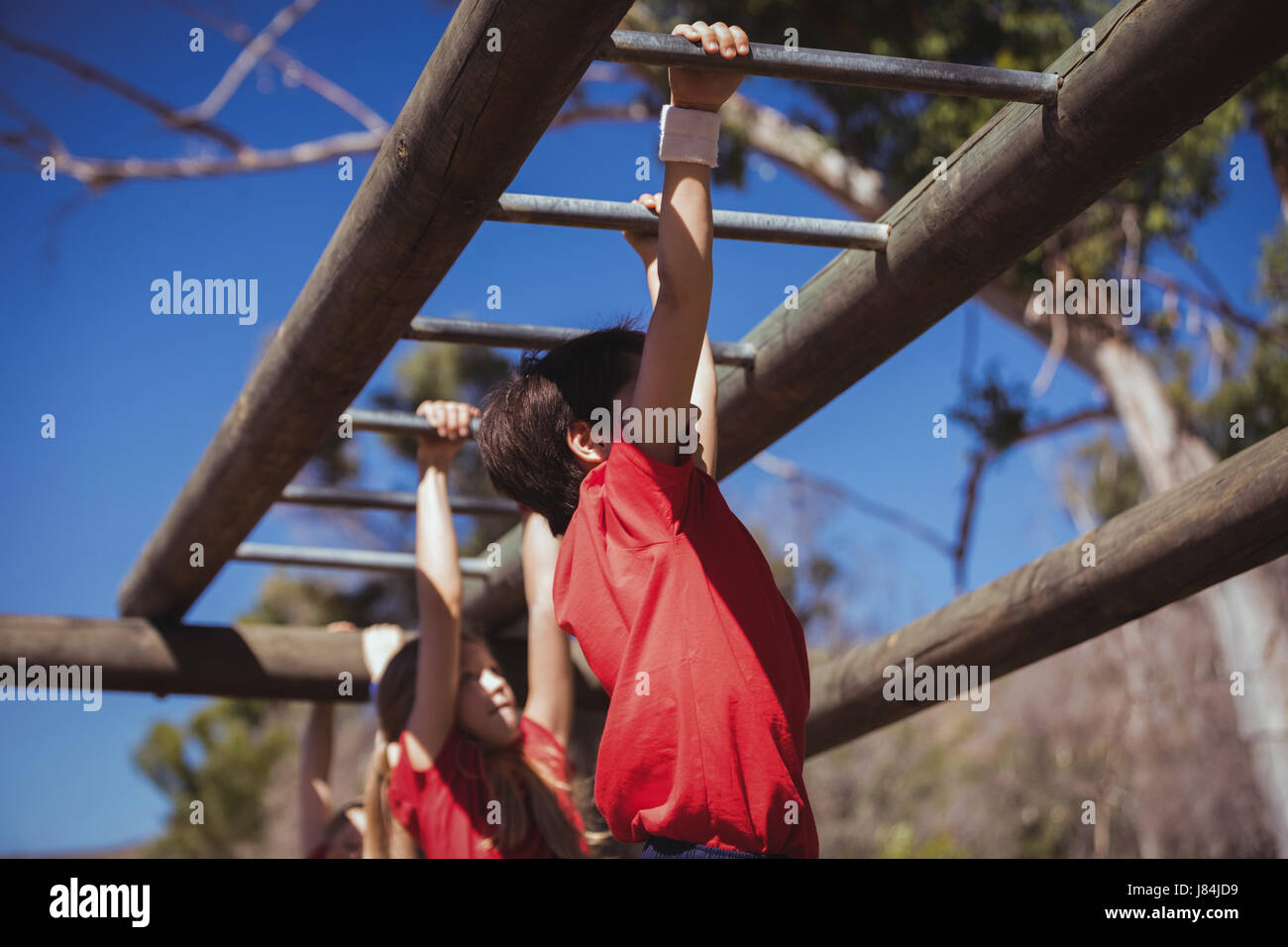 Kids climbing monkey bars during obstacle course training in the boot camp Stock Photo