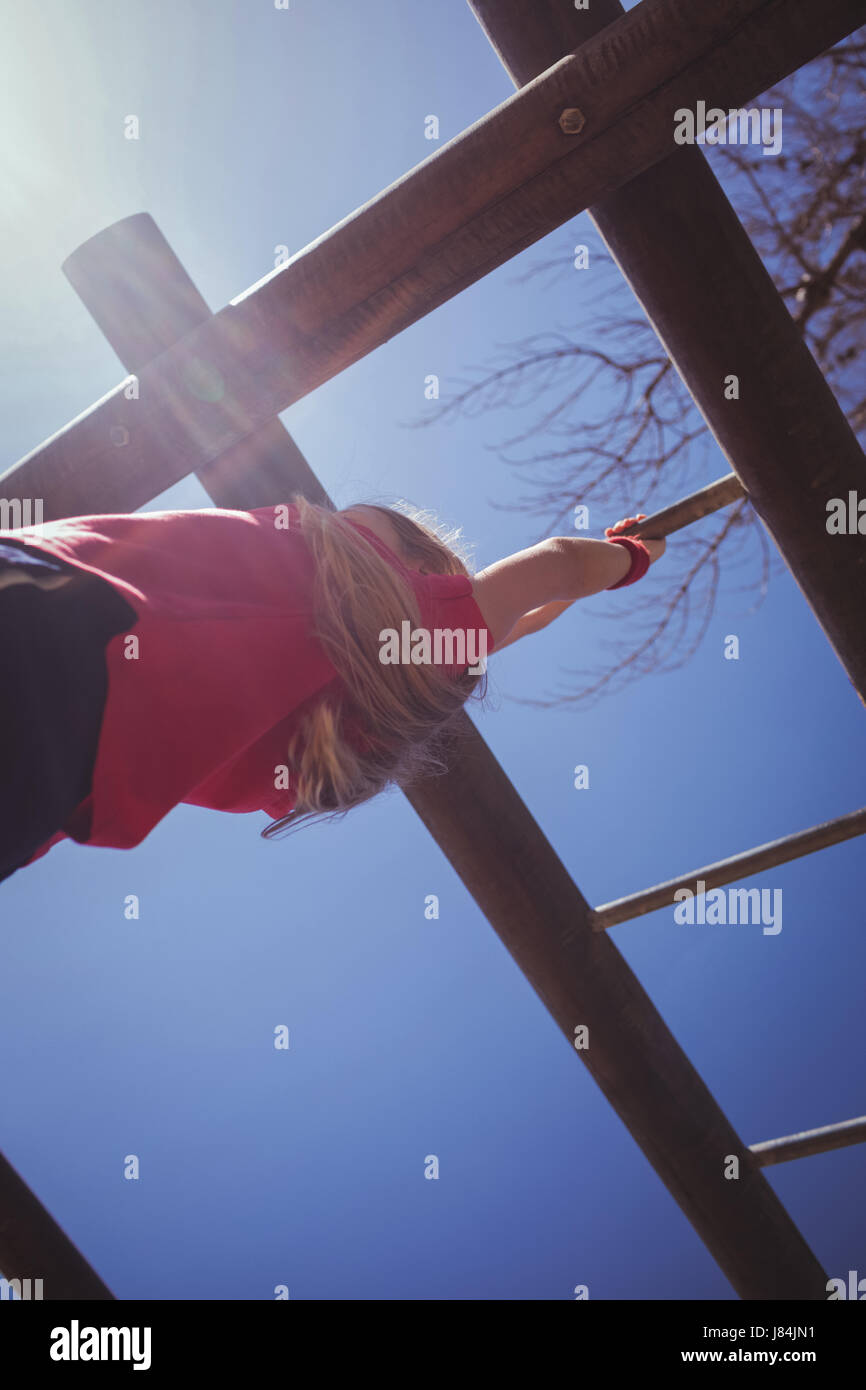Girl climbing monkey bars during obstacle course training at boot camp Stock Photo