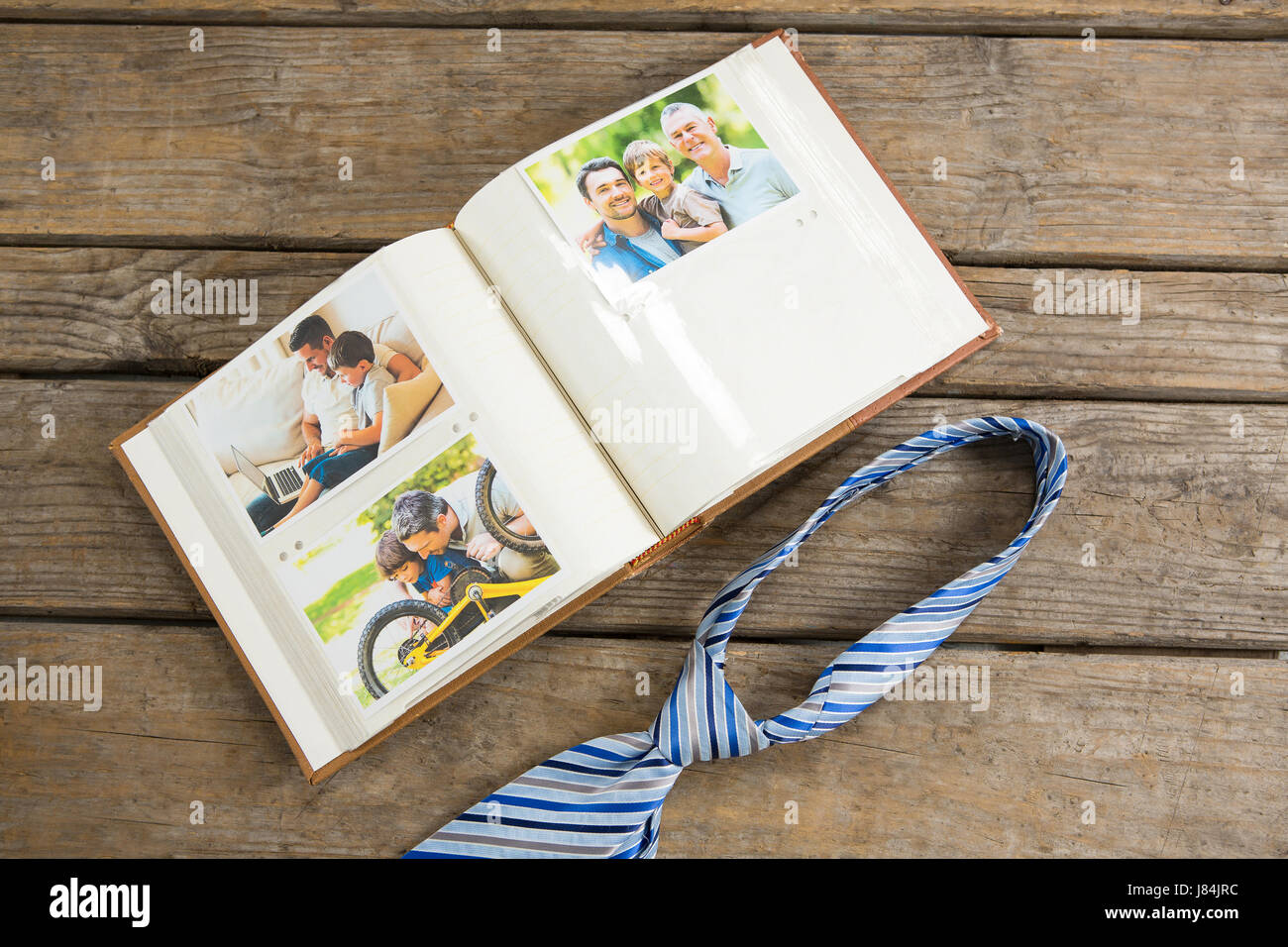 High angle view of photographs in book by necktie on table Stock Photo