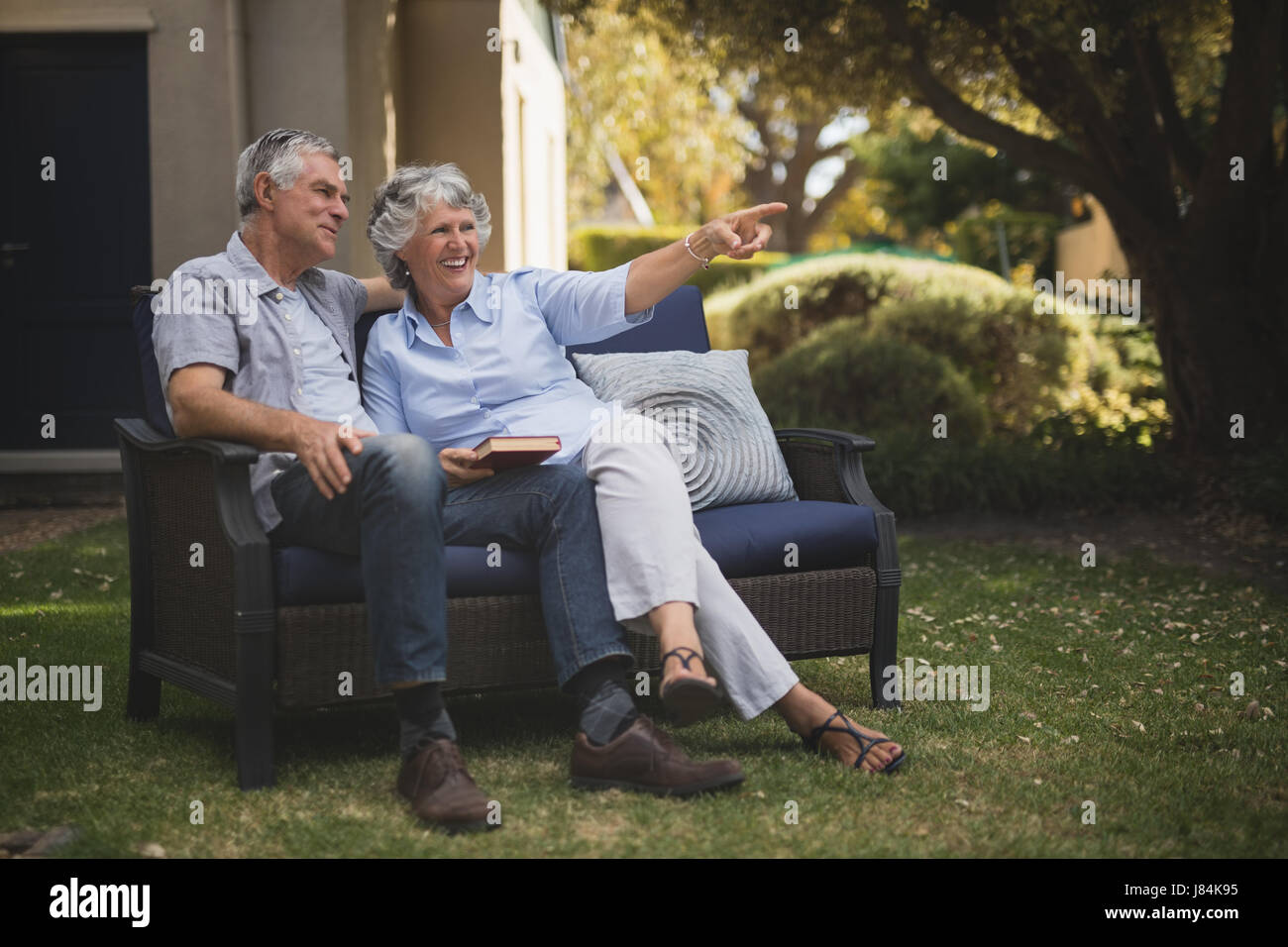 Happy senior couple sitting together on couch in backyard Stock Photo ...