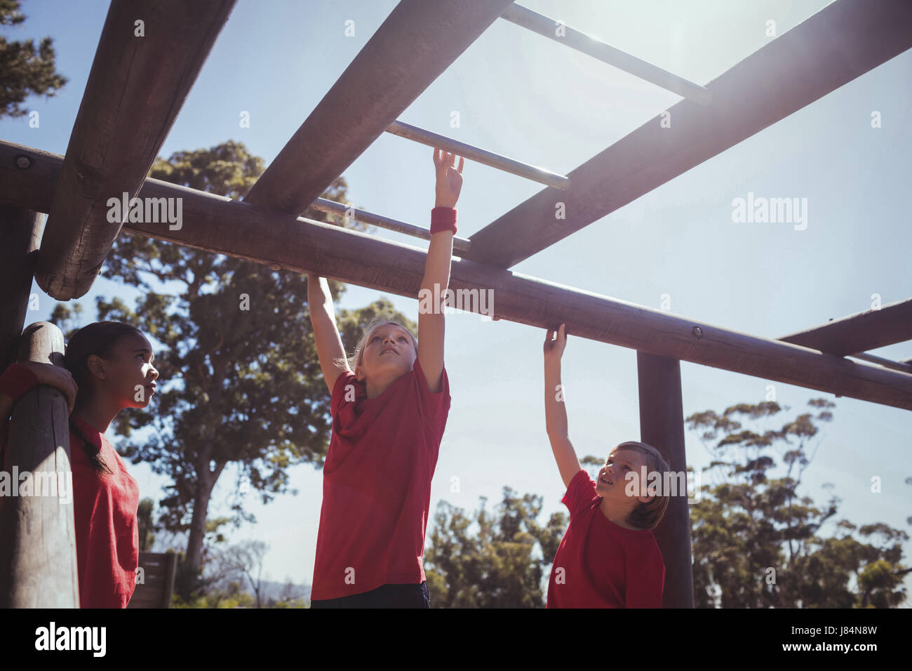 Kids climbing monkey bars during obstacle course training at boot camp Stock Photo