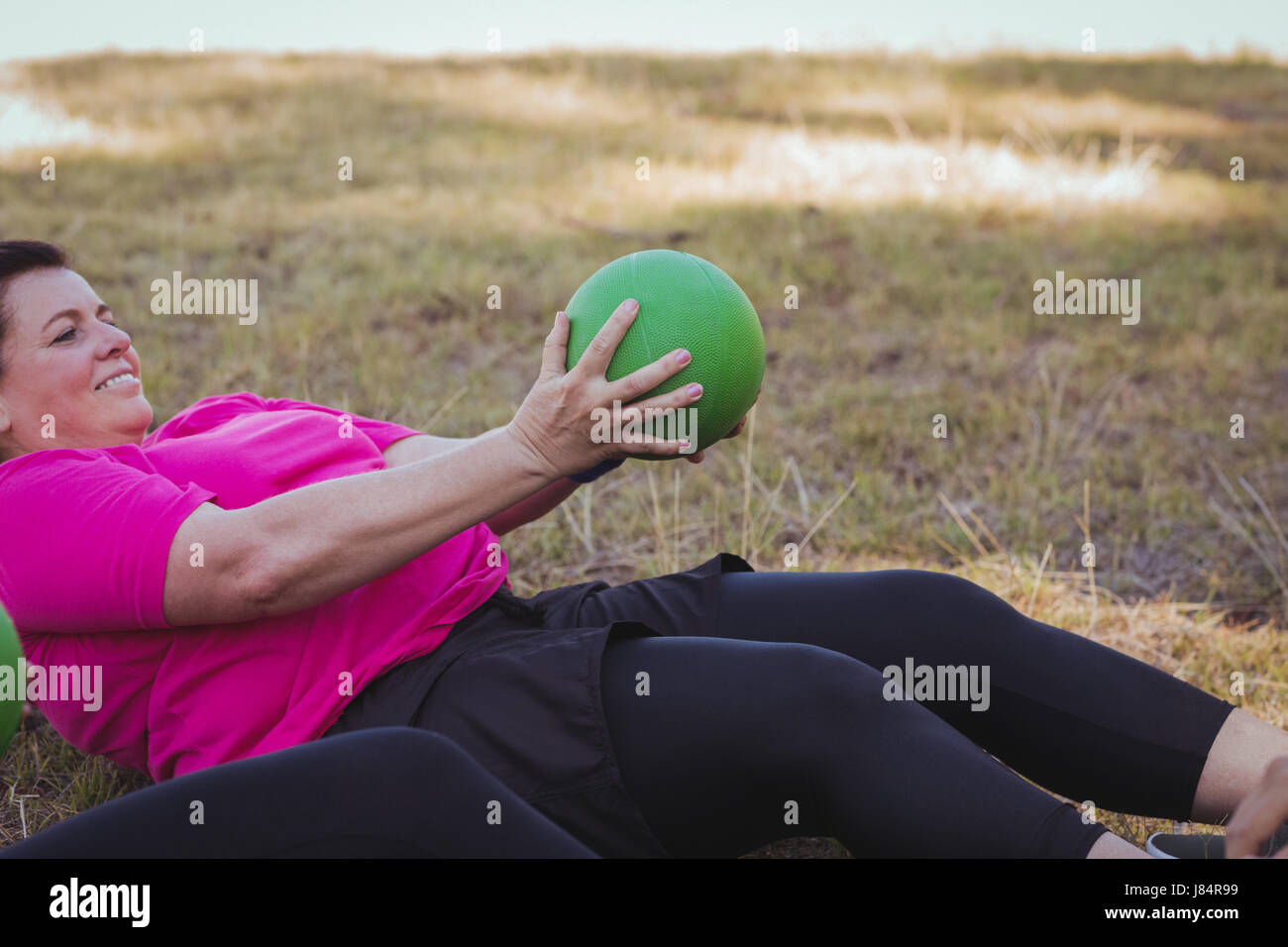 Women practicing ball sit up exercise in the boot camp on a sunny day Stock Photo