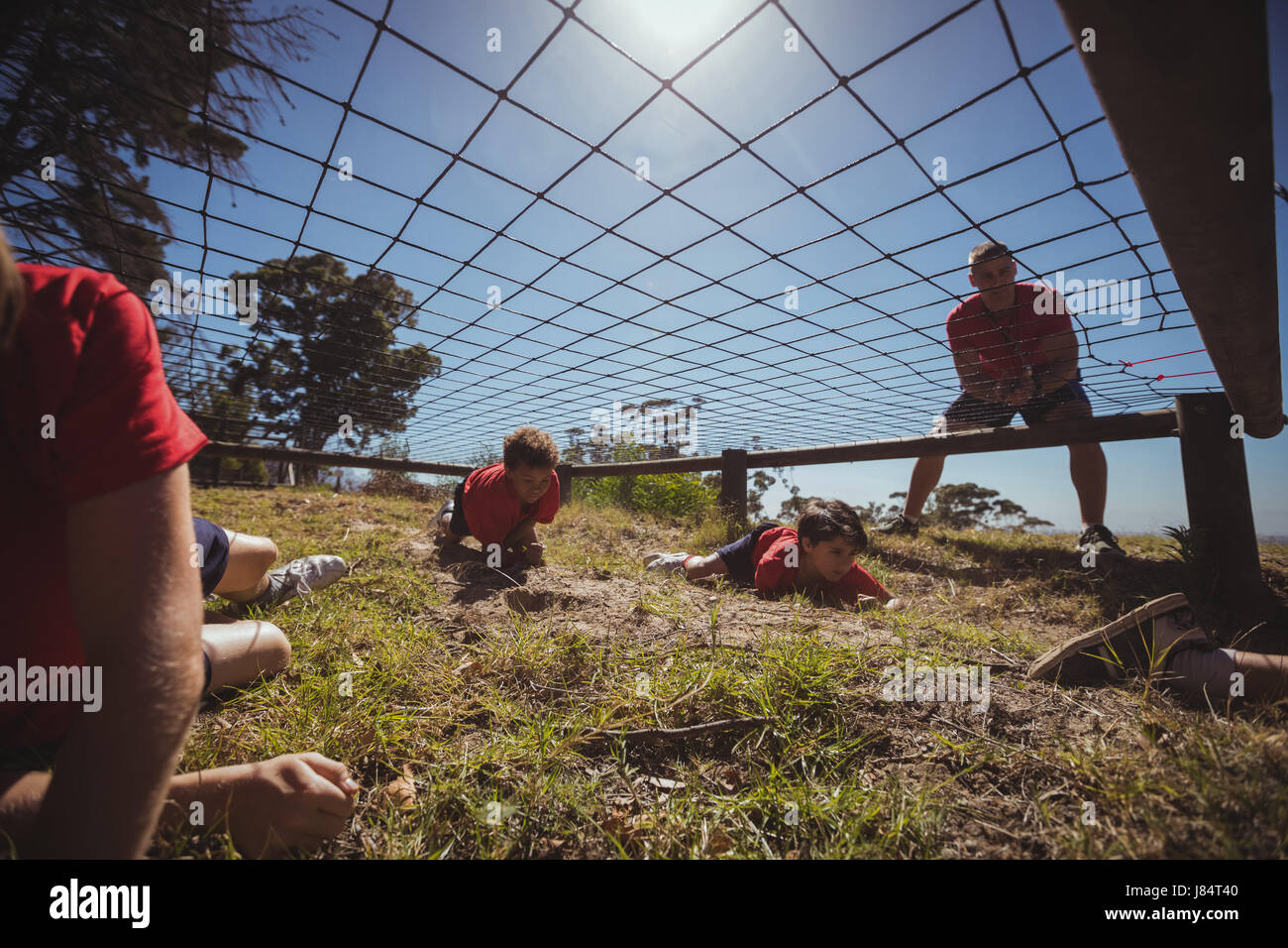 Kids crawling under the net during obstacle course training in the boot ...