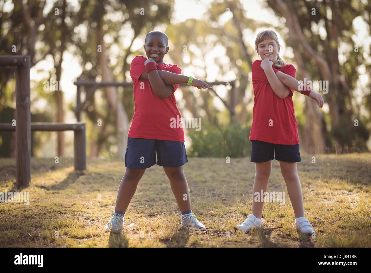 Portrait of happy kids performing stretching exercise during obstacle course in boot camp Stock Photo