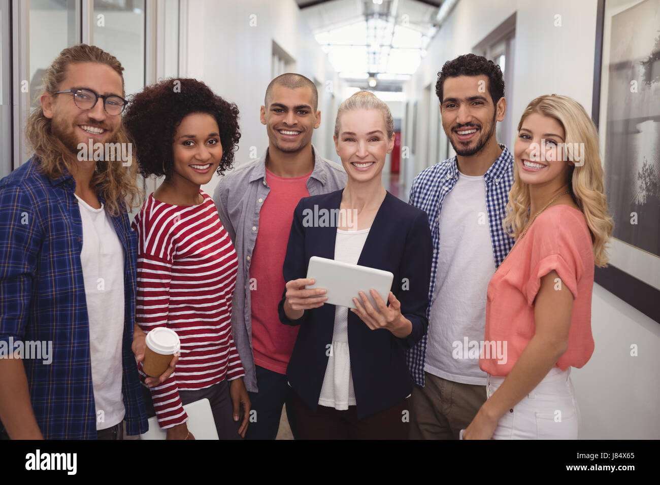 Portrait of smiling businesswoman team standing in corridor at creative ...